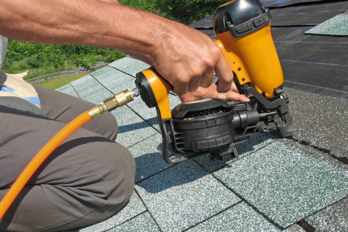 Roofer installing shingles with pneumatic roofing nailer