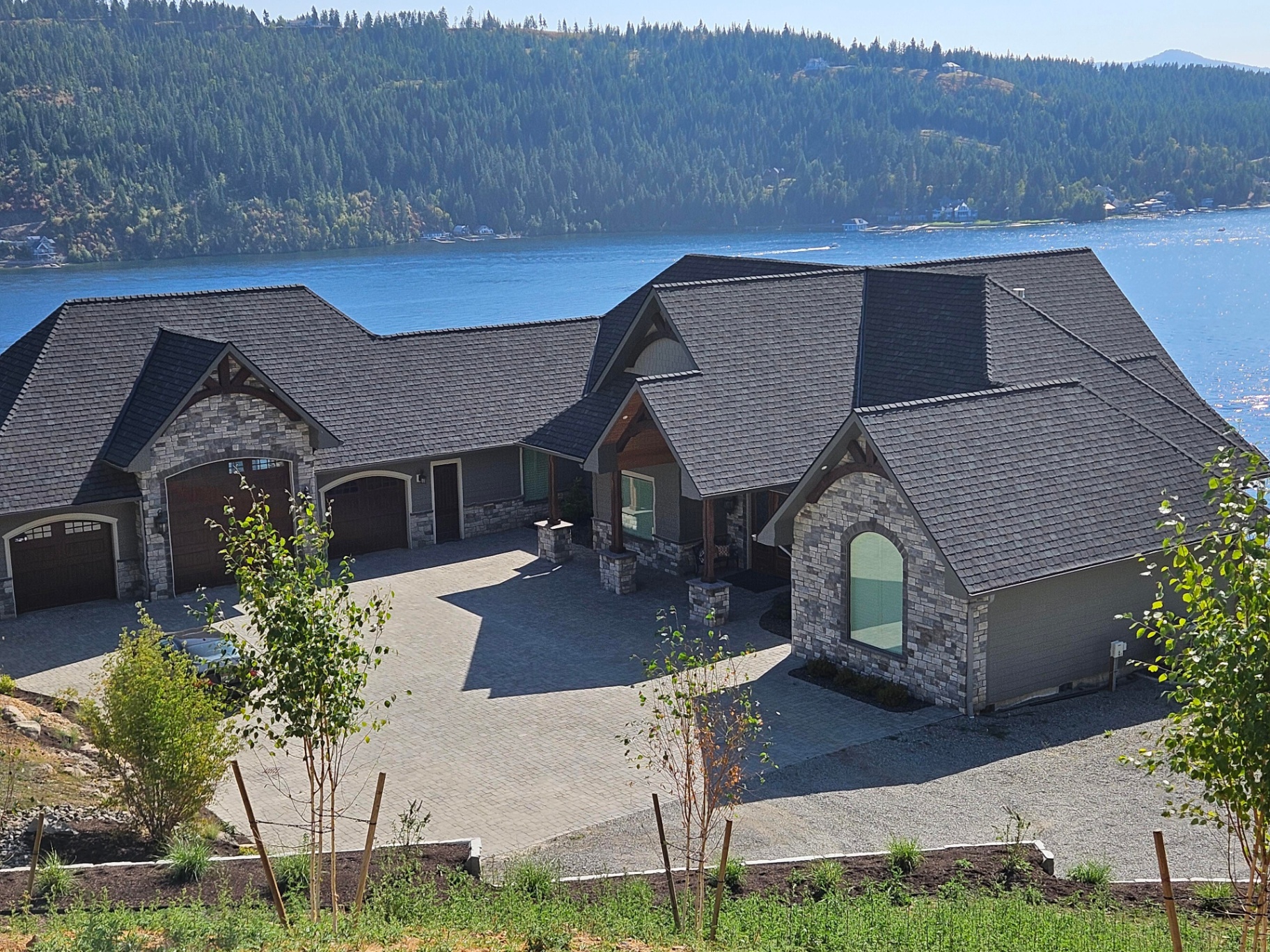 Luxury lakefront home with stone accents and premium black shingle roof